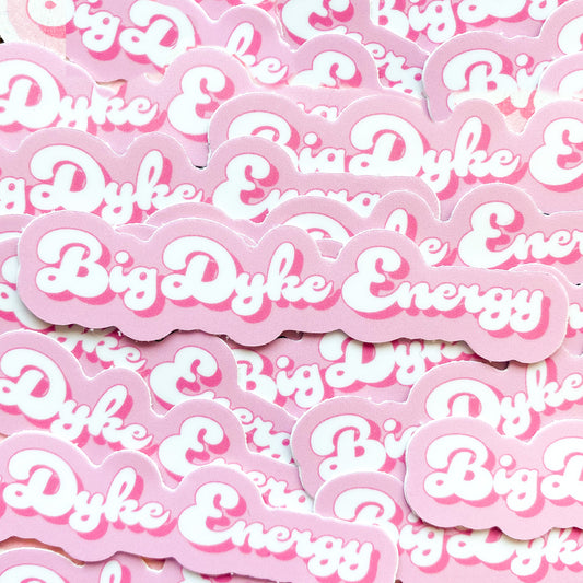 Photo of pink and white sticker with the  words 'big dyke energy', a funny lesbian pun.